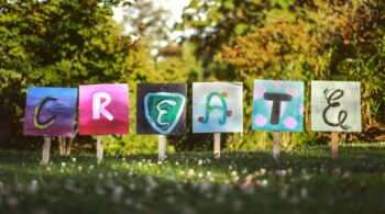 Wooden boards that have been staked into the grass, colourfully painted with letters to spell CREATE