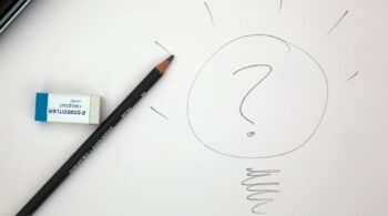 An eraser and pencil on a piece of paper with a drawing of a question mark inside a circle